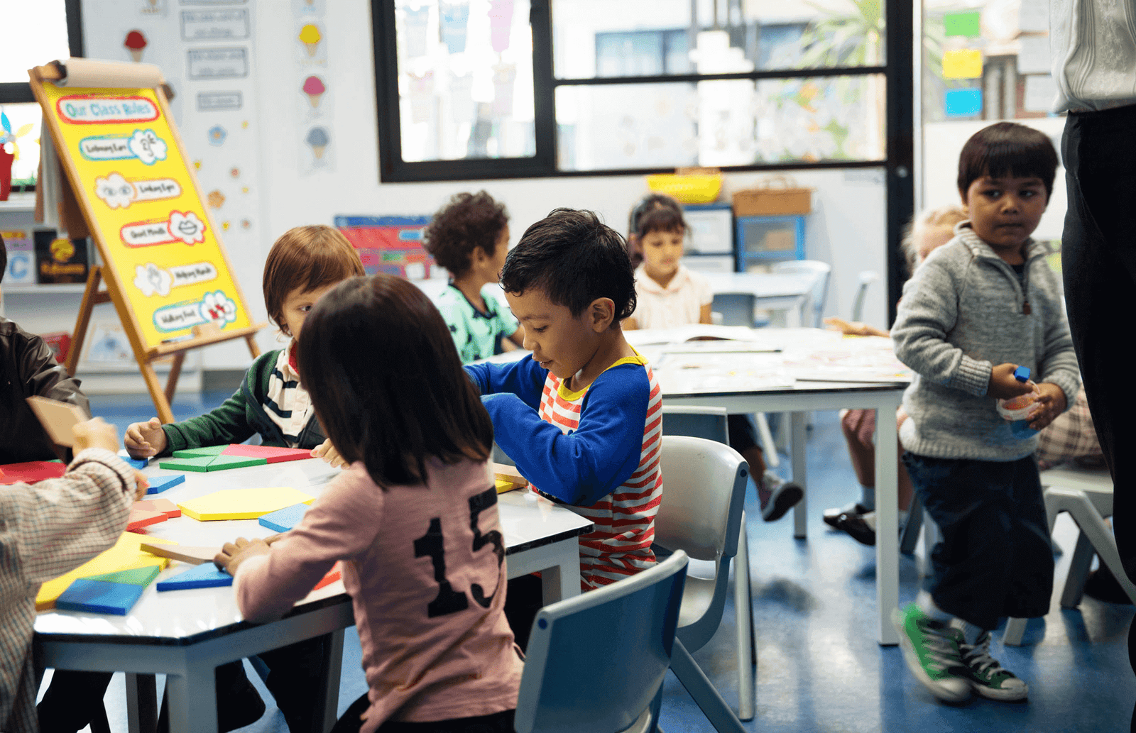 students sitting at a table playing with colorful shape puzzle blocks in a classroom
