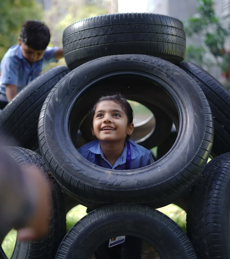 Schoolgirl Looking Through a Playground Tire